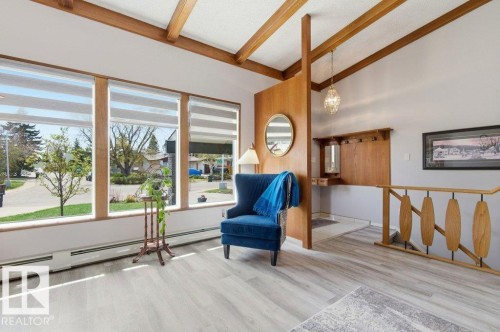 Spacious room featuring multiple large windows with layered shades, wood-finish flooring, and exposed wood ceiling beams - 8608 22 Ave, Edmonton, AB - Indoor Photo Showing Other Room