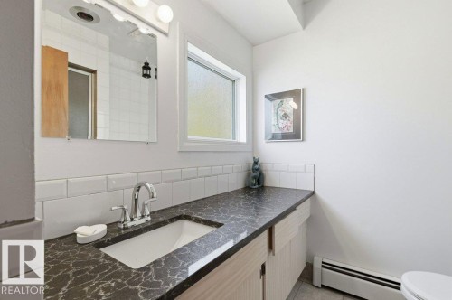 Bathroom vanity featuring a chrome faucet, integrated sink, and a dark patterned countertop - 8608 22 Ave, Edmonton, AB - Indoor Photo Showing Bathroom