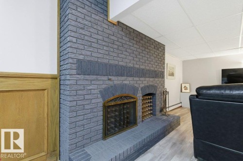 Brick fireplace with an integrated wine rack, hearth, and metal screen - 8608 22 Ave, Edmonton, AB - Indoor With Fireplace