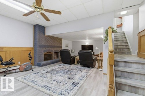 Finished lower level featuring a brick fireplace with integrated storage, light wood-finish flooring, and wainscoting - 8608 22 Ave, Edmonton, AB - Indoor With Fireplace