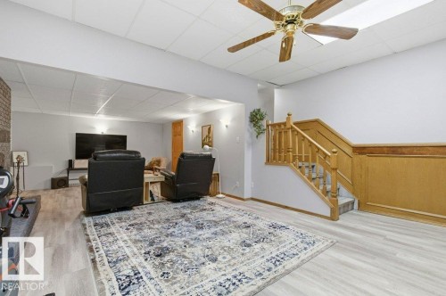 Finished lower level featuring light wood-finish flooring, a wood-paneled staircase, and a drop ceiling with recessed lighting - 8608 22 Ave, Edmonton, AB - Indoor