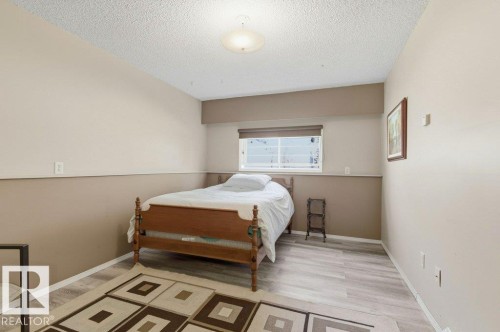 Room featuring wood-finish flooring, two-tone painted walls, and a single window with a roller shade - 8608 22 Ave, Edmonton, AB - Indoor Photo Showing Bedroom