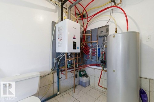 Utility area featuring a tankless water heater, traditional hot water heater, exposed copper piping, and a tiled floor - 8608 22 Ave, Edmonton, AB - Indoor