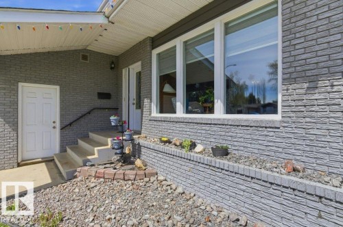 Stone-look exterior featuring multiple large windows - 8608 22 Ave, Edmonton, AB - Outdoor With Deck Patio Veranda