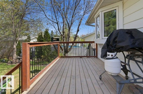 Spacious outdoor deck featuring wood-finish flooring and a stained wood railing with black metal balusters - 8608 22 Ave, Edmonton, AB - Outdoor With Deck Patio Veranda With Exterior