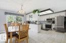 Open-concept kitchen and dining area featuring white cabinetry, stainless steel appliances, and a dark stone countertop - 8608 22 Ave, Edmonton, AB  - Indoor 