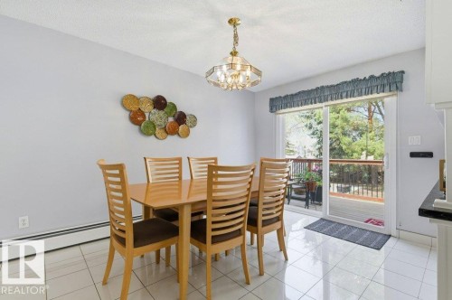 Dining area featuring light gray walls, a polished chandelier, and white square tile flooring - 8608 22 Ave, Edmonton, AB - Indoor Photo Showing Dining Room