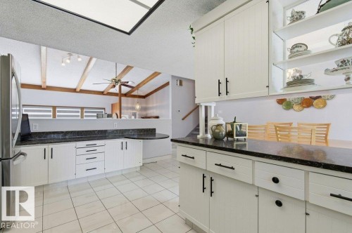 Kitchen featuring white cabinetry, dark countertops, and white tile flooring - 8608 22 Ave, Edmonton, AB - Indoor Photo Showing Kitchen