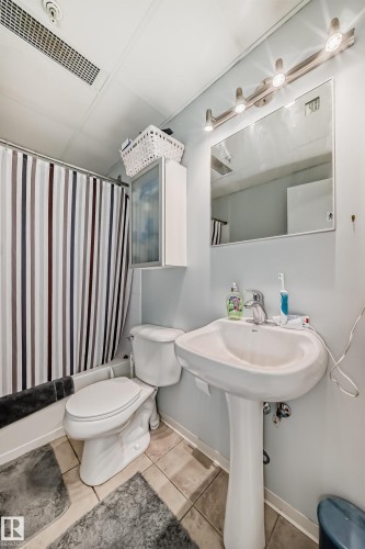 Bathroom featuring a pedestal sink, a toilet, and a shower with a striped curtain - 1207 10024 Jasper Avenue, Edmonton, AB - Indoor Photo Showing Bathroom