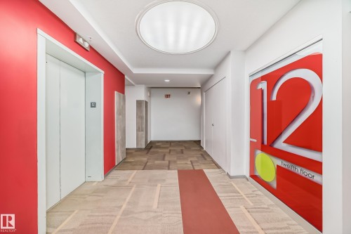 Modern hallway featuring a bright red accent wall and neutral patterned carpeting - 1207 10024 Jasper Avenue, Edmonton, AB - Indoor Photo Showing Other Room