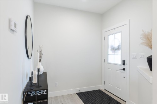 Entryway featuring a white paneled door with frosted glass insert, matte black hardware, and light wood-finish flooring - 1214 Eaton Lane, Edmonton, AB - Indoor Photo Showing Other Room