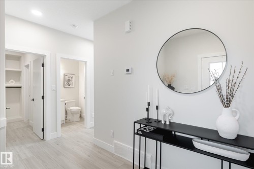 Hallway featuring light wood-finish flooring, white walls, recessed lighting, and a built-in closet with shelving and hanging rod - 1214 Eaton Lane, Edmonton, AB - Indoor Photo Showing Other Room