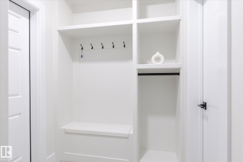 White built-in mudroom cabinetry featuring a bench, shelving, clothes hanging rod, and wall-mounted hooks - 1214 Eaton Lane, Edmonton, AB - Indoor With Storage