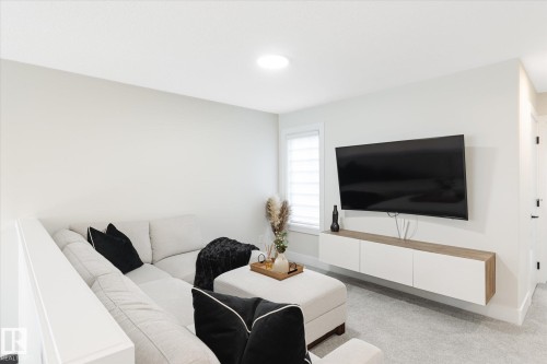 Recessed overhead lighting, light-toned carpeting, a floating media console with wood-finish accents, and a window with horizontal blinds - 1214 Eaton Lane, Edmonton, AB - Indoor Photo Showing Living Room