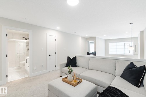 Carpeted lounge area featuring a partial wall, recessed lighting, and a contemporary hanging light fixture - 1214 Eaton Lane, Edmonton, AB - Indoor Photo Showing Living Room