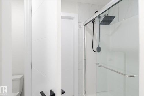 Contemporary shower enclosure featuring a rain shower head, hand-held sprayer, clear glass, and a sliding door with a chrome handle - 1214 Eaton Lane, Edmonton, AB - Indoor Photo Showing Bathroom