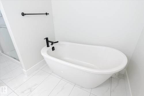 Freestanding oval bathtub with matte black fixtures - 1214 Eaton Lane, Edmonton, AB - Indoor Photo Showing Bathroom