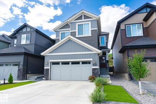 Modern residential exterior featuring a light gray garage door, dark gray siding, white trim, and stone veneer accents - 1214 Eaton Lane, Edmonton, AB - Outdoor With Facade