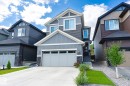 Modern residential exterior featuring a light gray garage door, dark gray siding, white trim, and stone veneer accents - 1214 Eaton Lane, Edmonton, AB  - Outdoor With Facade 