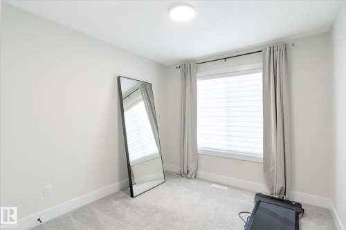 Room featuring light gray carpeting, neutral wall paint, and a white window frame with horizontal blinds - 1214 Eaton Lane, Edmonton, AB - Indoor