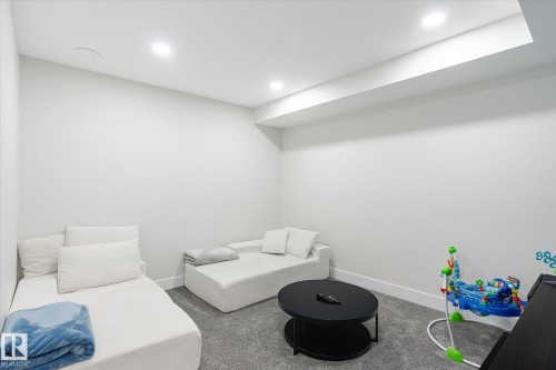 Recessed lighting illuminating a spacious room with light gray walls, plush gray carpeting, and white baseboards - 1214 Eaton Lane, Edmonton, AB - Indoor