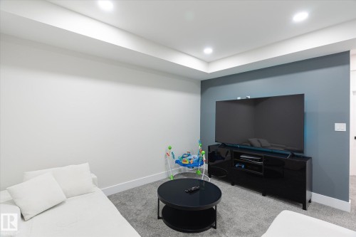 Recessed lighting illuminates a carpeted room featuring a ceiling soffit and a contrasting accent wall - 1214 Eaton Lane, Edmonton, AB - Indoor