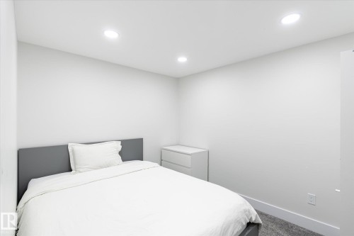 Bedroom featuring recessed ceiling lighting, a dark gray headboard, white walls, and gray carpet - 1214 Eaton Lane, Edmonton, AB - Indoor Photo Showing Bedroom