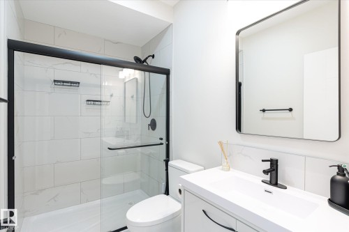 Contemporary bathroom featuring a frameless glass shower with black trim, a wall-mounted showerhead, and integrated shelving - 1214 Eaton Lane, Edmonton, AB - Indoor Photo Showing Bathroom
