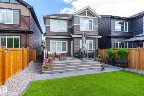 Rear exterior with a multi-level composite deck, a lower patio area, and a lush green lawn - 1214 Eaton Lane, Edmonton, AB - Outdoor