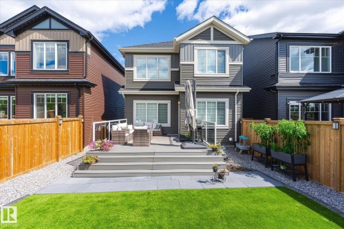 Rear exterior featuring a multi-level composite deck, a lower patio, and a manicured lawn - 1214 Eaton Lane, Edmonton, AB - Outdoor