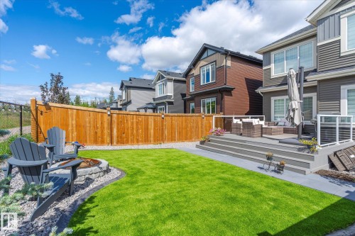 Expansive backyard featuring a tiered composite deck, a stone fire pit area, a well-maintained lawn, and a tall wood privacy fence - 1214 Eaton Lane, Edmonton, AB - Outdoor