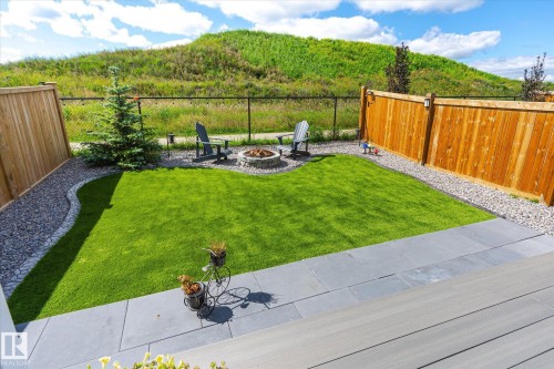 Backyard featuring a stone-lined fire pit, manicured lawn, and a perimeter of decorative gravel - 1214 Eaton Lane, Edmonton, AB - Outdoor