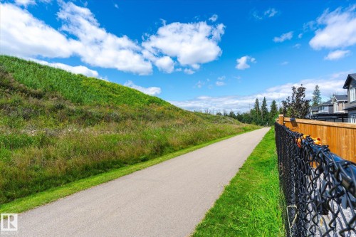 Paved pathway bordered by a chain link fence, a natural wood fence, and a grassy incline - 1214 Eaton Lane, Edmonton, AB - Outdoor With View
