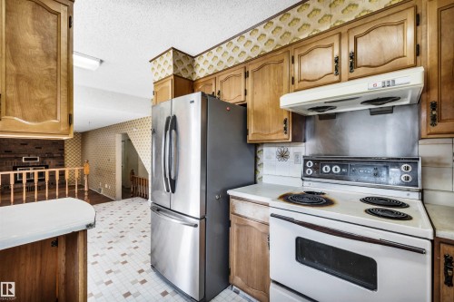 Kitchen featuring wood cabinetry, a white electric range, and a stainless steel refrigerator - 6723 39 Avenue, Edmonton, AB - Indoor Photo Showing Kitchen