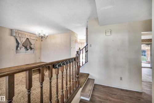 Split-level interior featuring wood-finish flooring, a traditional wood railing, and a crystal chandelier - 6723 39 Avenue, Edmonton, AB - Indoor Photo Showing Other Room