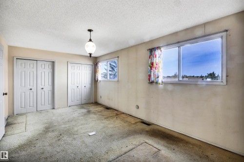 Room featuring two sets of bi-fold closet doors, a ceiling-mounted light fixture, and two windows providing natural illumination - 6723 39 Avenue, Edmonton, AB - Indoor