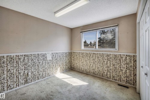 Room featuring a window, textured wallpaper wainscoting, light-toned upper walls, and a fluorescent ceiling fixture - 6723 39 Avenue, Edmonton, AB - Indoor Photo Showing Other Room