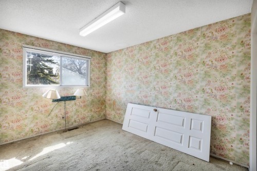 Room featuring a large window, textured ceiling, and floral wallpaper - 6723 39 Avenue, Edmonton, AB - Indoor Photo Showing Other Room