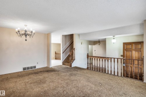 Spacious living area featuring a decorative chandelier, textured ceilings, and wall-to-wall carpeting - 6723 39 Avenue, Edmonton, AB - Indoor Photo Showing Other Room