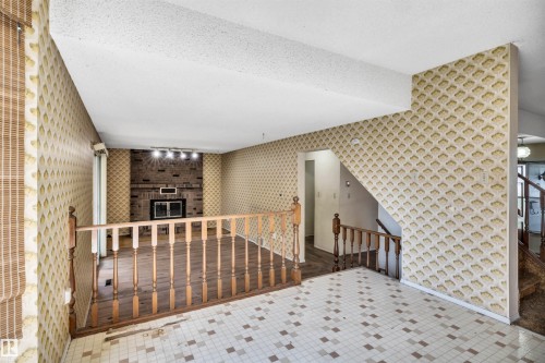 Split-level interior featuring wood-finish flooring, a brick fireplace with a dark metal insert, and patterned wallpaper - 6723 39 Avenue, Edmonton, AB -  With Exterior