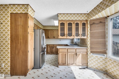 Kitchen featuring wood-finish cabinetry, white countertops, and patterned wall covering - 6723 39 Avenue, Edmonton, AB -  With Exterior
