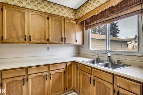 Kitchen featuring extensive wood cabinetry, white countertops, and a dual basin stainless steel sink - 6723 39 Avenue, Edmonton, AB - Indoor Photo Showing Kitchen With Double Sink