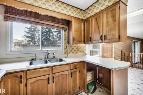 Kitchen featuring wood cabinetry, a double basin stainless steel sink, and white countertops - 6723 39 Avenue, Edmonton, AB - Indoor Photo Showing Kitchen With Double Sink