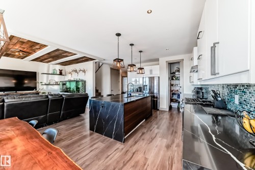 Open-concept living space featuring wood-finish flooring, a kitchen island with stone waterfall countertops, and white cabinetry - 5263 47 Ave, Calmar, AB - Indoor Photo Showing Kitchen