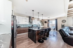 Modern kitchen featuring an expansive center island with waterfall countertop, stainless steel appliances, and a mosaic tile backsplash - 
