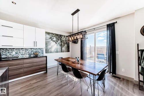 Open concept room featuring wood-finish flooring, a contemporary dining chandelier, and a sliding glass door providing access to an outdoor patio - 5263 47 Ave, Calmar, AB - Indoor Photo Showing Dining Room
