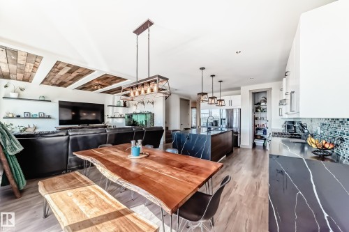 Open-concept living space featuring wood-finish flooring, a kitchen with dark countertops and a mosaic tile backsplash, and a dining area with a live-edge wood table - 5263 47 Ave, Calmar, AB - Indoor Photo Showing Dining Room