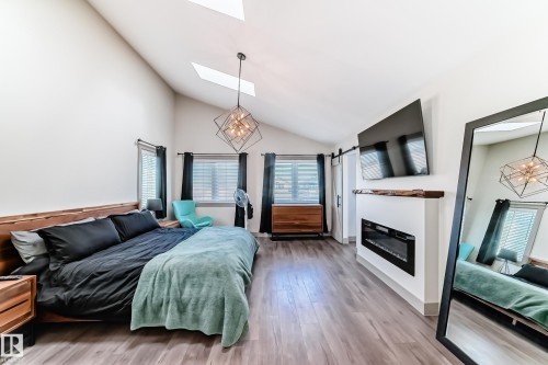 Vaulted ceiling featuring skylights and a geometric chandelier - 5263 47 Ave, Calmar, AB - Indoor Photo Showing Bedroom With Fireplace