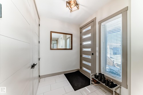 Entryway featuring white tile flooring, a contemporary front door with horizontal glass panels, and an adjacent full-height window - 5263 47 Ave, Calmar, AB - Indoor Photo Showing Other Room