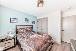 Bedroom featuring wood-finish flooring, a light blue accent wall, modern ceiling light fixture, and two panel doors - 